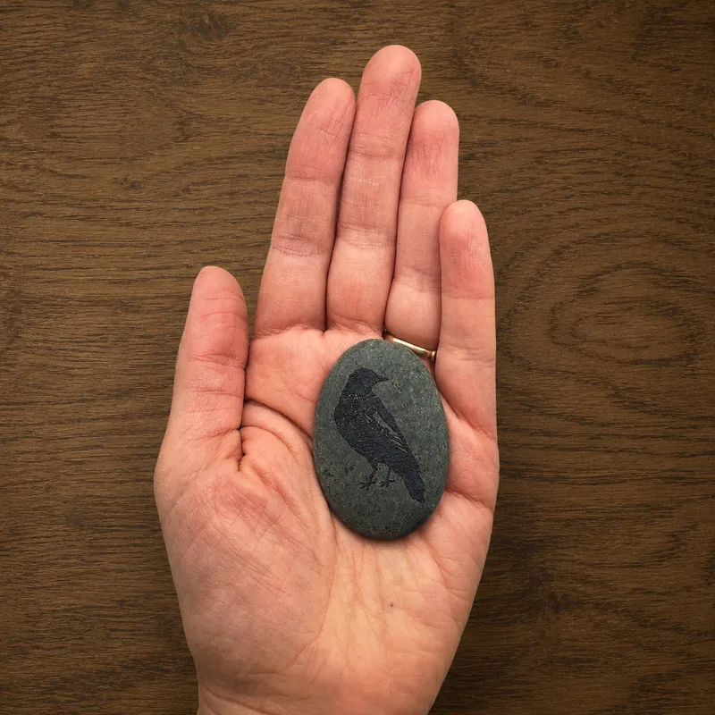 Coven's familiar — raven-engraved river rock, landscape view