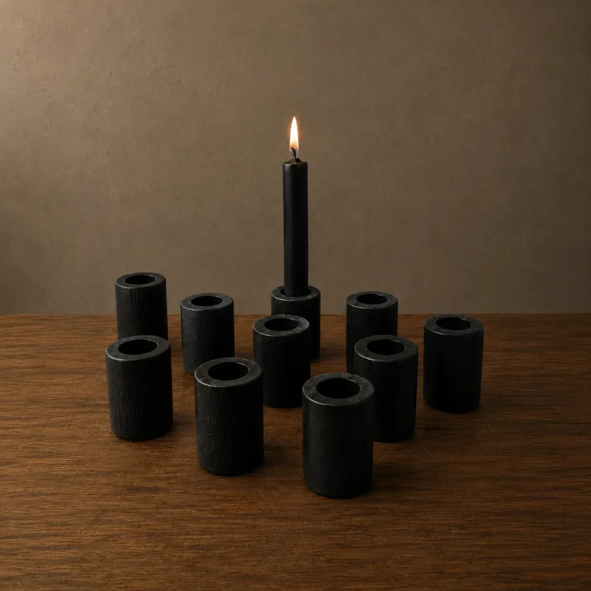 Ritual candle holder — a cluster of matte-black cast-iron ritual candle holders on a wood surface, one holding a lit black candle