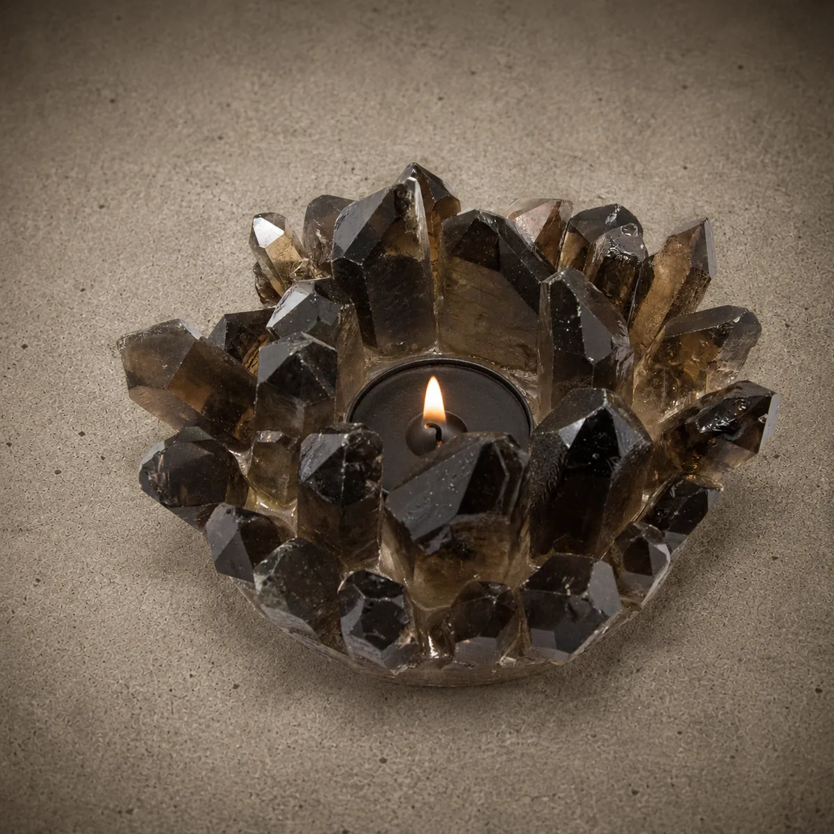 Quartz candle holder — a cluster of smoky quartz points forming a bowl, holding a lit tea light, on a concrete surface