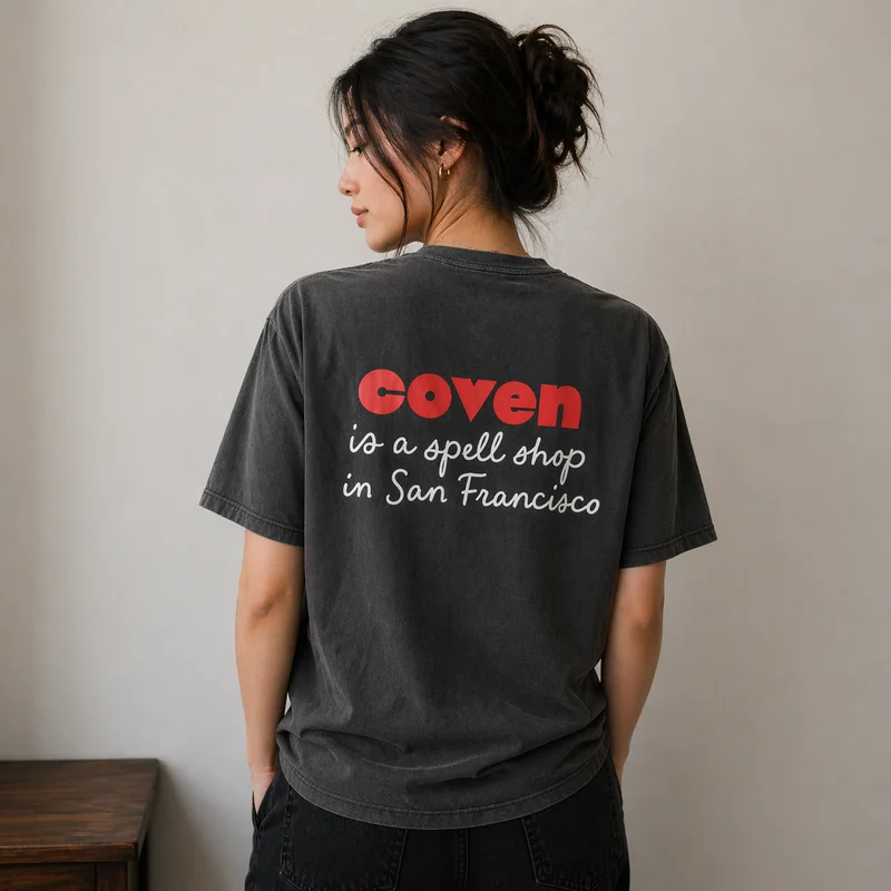 The back of The Uniform — the Coven wordmark in red with 'is a spell shop in San Francisco' handwritten below in white